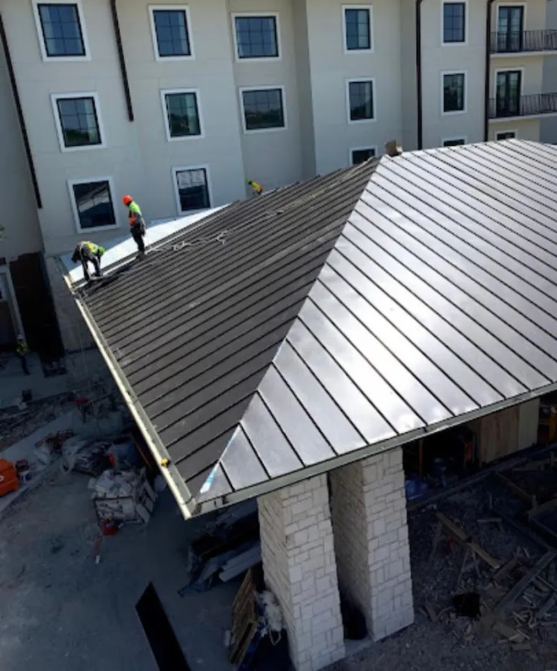Crew installing standing seam metal roof panels on a commercial project in Guilderland
